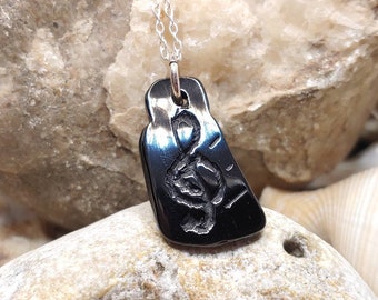 Può includere: Una collana con un ciondolo nero a forma di chiave di violino su una catena d'argento.