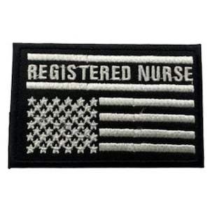 Può includere: Toppa rettangolare nera con testo e disegno ricamati in bianco. Il testo recita "REGISTERED NURSE" sopra una bandiera americana stilizzata. La bandiera presenta stelle e strisce bianche.