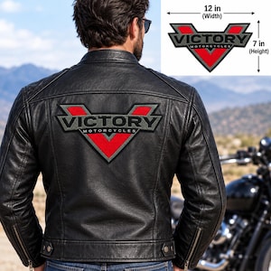 May include: A black leather jacket featuring a large embroidered patch on the back with a red V shape, grey borders, and the text VICTORY MOTORCYCLES. The patch measures 30.48 cm in width and 17.78 cm in height as indicated in the inset graphic.