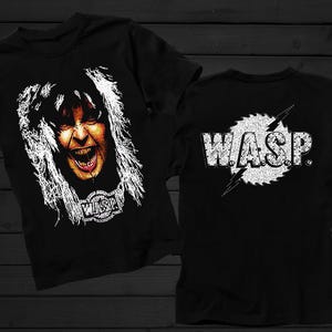 Könnte beinhalten: Schwarze T-Shirts mit einem Rockband-Motiv. Auf der Vorderseite des Shirts ist ein schreiendes Gesicht mit weißen Haaren und das Logo der Band abgebildet. Auf der Rückseite steht der Bandname W.A.S.P. in Weiß.