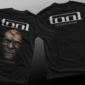 Op de afbeelding: Zwart T-shirt met een witte afbeelding van een schedel met een derde oog en de tekst "Tool 10,000 Days". De achterkant van het shirt heeft de tekst "Tool 10,000 Days" in wit.