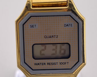 Relógio de pulso vintage sem marca, em tom dourado, digital, com pulseira expansível, década de 1980.