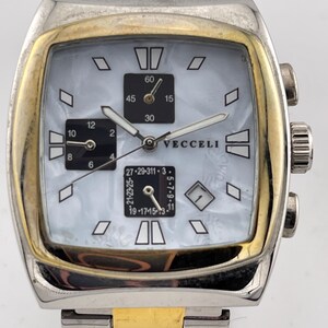 May include: A silver and gold-toned Vecelli watch with a square face and a mother-of-pearl dial. The watch features black subdials, diamond-shaped hour markers, and a gold-toned bezel. The watch band is a combination of silver and gold links.