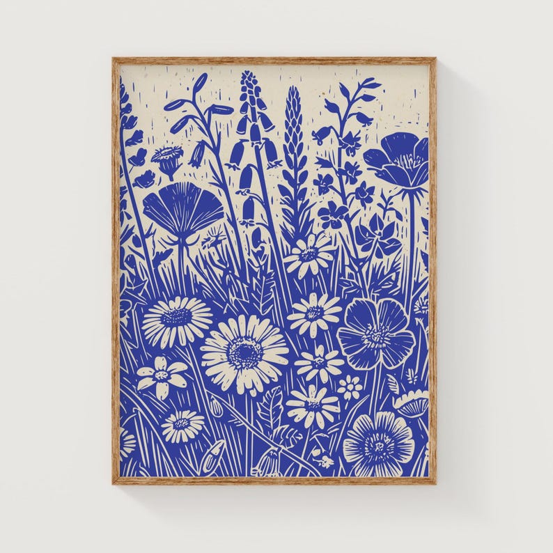 May include: A blue and white linocut print of a variety of flowers in a field. The print is framed in a natural wood frame.