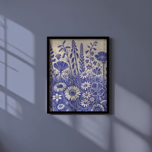 May include: A framed print of a blue and white floral design. The print features a variety of flowers, including daisies, poppies, and bellflowers. The background is a light beige color.