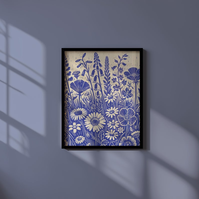 May include: A framed print of a blue and white floral design. The print features a variety of flowers, including daisies, poppies, and bellflowers. The background is a light beige color.
