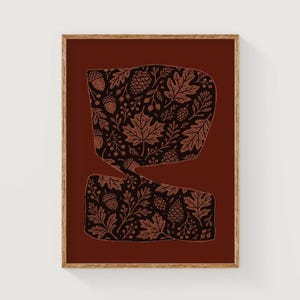 May include: A framed art print featuring a dark red background with two abstract shapes. The shapes are filled with a detailed pattern of leaves, acorns, and pinecones in shades of brown and black. The wooden frame adds a natural touch.