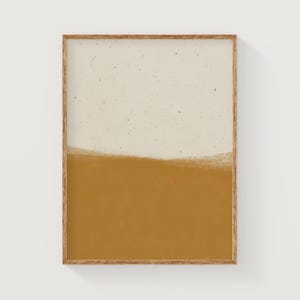 Könnte beinhalten: Ein gerahmter abstrakter Kunstdruck mit einer weißen oberen Hälfte und einer senfgelben unteren Hälfte. Der Druck hat eine strukturierte, gesprenkelte Optik.