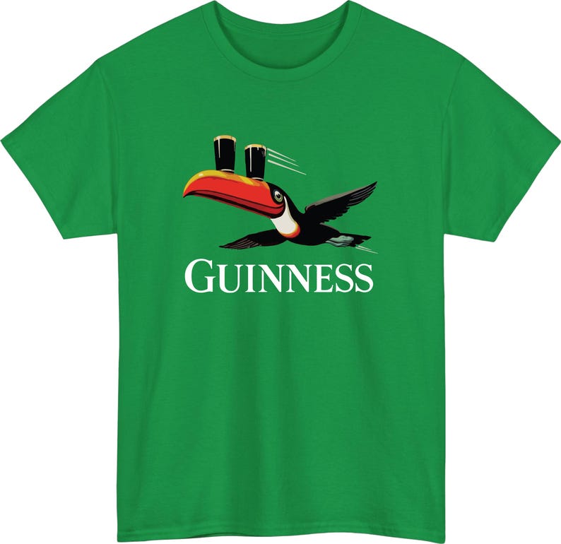 May include: Green t-shirt featuring a toucan with a red beak and black wings, carrying two pints of dark beer. The word "GUINNESS" is printed in white below the bird. A fun and casual design.