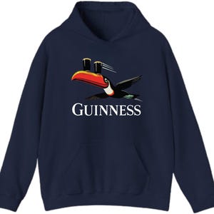May include: Navy blue hooded sweatshirt featuring the Guinness logo with a toucan carrying two pints of beer. The toucan has a red, orange, and black beak and is in flight. The word "GUINNESS" is printed in white.