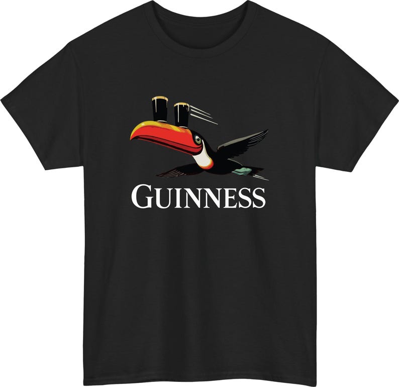 May include: Black t-shirt featuring a toucan with a red and orange beak, carrying two pints of stout. The word "GUINNESS" is printed in white below the bird. A classic design for fans of the Irish stout.