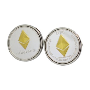 May include: Silver-toned cufflinks featuring the Ethereum logo. Each cufflink has a silver background with a gold Ethereum symbol and the word "ethereum" or text that reads "DECENTRALIZED PLATFORM THAT RUNS SMART CONTRACTS".