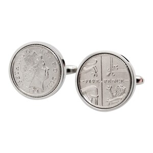 May include: Silver cufflinks featuring a replica of a British five pence coin. One cufflink shows the profile of Queen Elizabeth II, the other shows the reverse side of the coin with the inscription "FIVE PENCE".