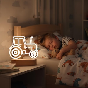May include: A wooden tractor-shaped night light with the name "Henry" illuminated in white. The light sits on a wooden base and is placed on a nightstand next to a bed. A child is sleeping in the bed, clutching a teddy bear.