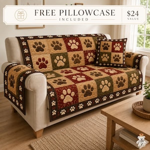May include: A quilted sofa cover featuring a patchwork design of alternating squares in shades of tan, dark red, and olive green, each decorated with dark brown paw prints. The cover includes a matching square throw pillow with the same pattern.
