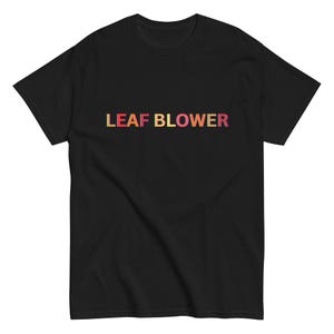 Peut inclure: T-shirt noir avec l'inscription "LEAF BLOWER" en lettres multicolores dégradées sur la poitrine. Le texte passe du rouge au jaune, créant un contraste vif. Un vêtement décontracté pour un usage quotidien.