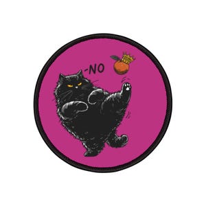Op de afbeelding: Ronde patch met een zwarte kat die een sinaasappel met een kroon trapt. De kat heeft gele ogen en het woord "-NO" staat boven de kat. De achtergrond is magenta met een zwarte rand.