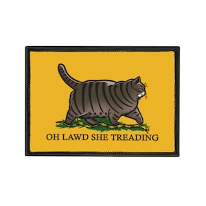 Pode incluir: Um patch retangular com uma borda preta e um fundo amarelo. Um gato de desenho animado com listras marrons caminha sobre um pedaço de grama verde. O texto "OH LAWD SHE TREADING" é impresso em preto abaixo.