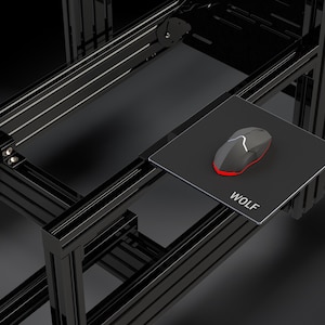 Könnte beinhalten: Eine schwarze Computermaus mit roten Akzenten und weißem Design liegt auf einem schwarzen Mauspad. Auf dem Mauspad steht "WOLF" in weißer Schrift. Maus und Pad befinden sich auf einem schwarzen Metallrahmen.