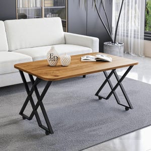 Peut inclure: Une table basse rectangulaire avec un plateau en bois clair à grain apparent et un cadre en métal noir doté de pieds en forme de X. La table est équipée de petites roulettes à la base de chaque pied et présente des coins arrondis.