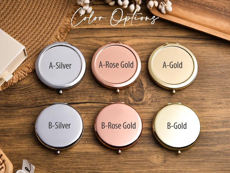 May include: A collection of six round compact mirrors in silver, rose gold, and gold finishes. Each mirror is labeled with a letter and color name, such as "A-Silver" and "B-Gold". The text "Color Options" is displayed in a script font.