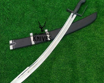 May include: A curved sword with a silver blade and black handle rests on a black sheath. The sword has a crossguard and a curved blade. The sheath is black with silver accents. The text "US SURVIVAL KNIVES" is visible.