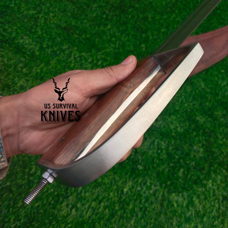 Pode incluir: Uma faca com cabo de madeira e l&acirc;mina prateada. A faca tem um formato &uacute;nico e &eacute; segurada na m&atilde;o. O texto "US SURVIVAL KNIVES" est&aacute; impresso no cabo.