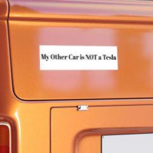 May include: A close-up of a vintage orange van with a white bumper sticker that reads "My Other Car is NOT a Tesla".