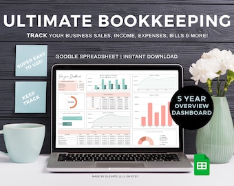 May include: A laptop computer displaying a Google spreadsheet with a 5-year overview dashboard for business bookkeeping. The spreadsheet includes charts and graphs with data for sales, income, expenses, and bills. The laptop is on a white surface with a light blue mug and a vase of white flowers.