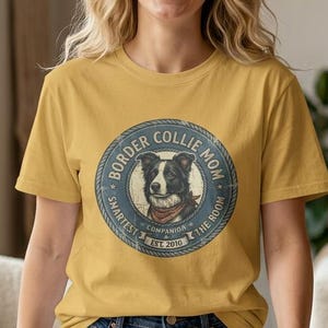 May include: Mustard yellow t-shirt with a circular graphic. The graphic features a Border Collie illustration and the text "Border Collie Mom." The design is in a blue circle with the words "Smartest Companion in the Room" and "Est. 2010."