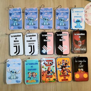 Puede incluir: Una colección de llaveros personalizados con varios diseños. Algunos presentan al personaje Stitch, otros tienen nombres como "Mirko" y "Francesco" con un logotipo del Juventus, y otros personajes de dibujos animados. Los llaveros son rectangulares con esquinas redondeadas.