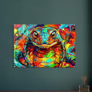 Puede incluir: Una pintura vibrante y colorida de la cabeza de una serpiente. La obra presenta una vista de cerca de la serpiente con azules, naranjas, amarillos y rojos brillantes. Los ojos de la serpiente son de un marrón cálido y el fondo es una salpicadura de colores.