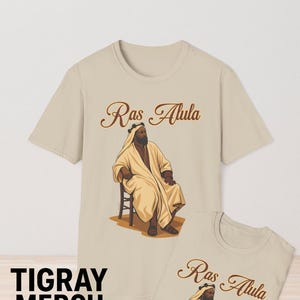 May include: Two beige t-shirts with a brown graphic of a man wearing a turban and robe. The text "Ras Alula" is printed on both shirts.
