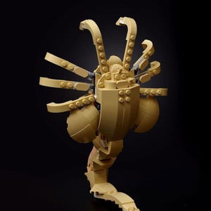 Pode incluir: Um modelo Lego bege de uma criatura alien&iacute;gena com v&aacute;rios bra&ccedil;os e uma cauda segmentada.