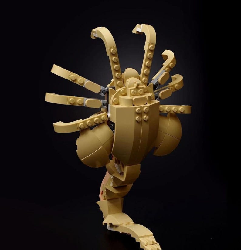 Pode incluir: Um modelo Lego bege de uma criatura alien&iacute;gena com v&aacute;rios bra&ccedil;os e uma cauda segmentada.