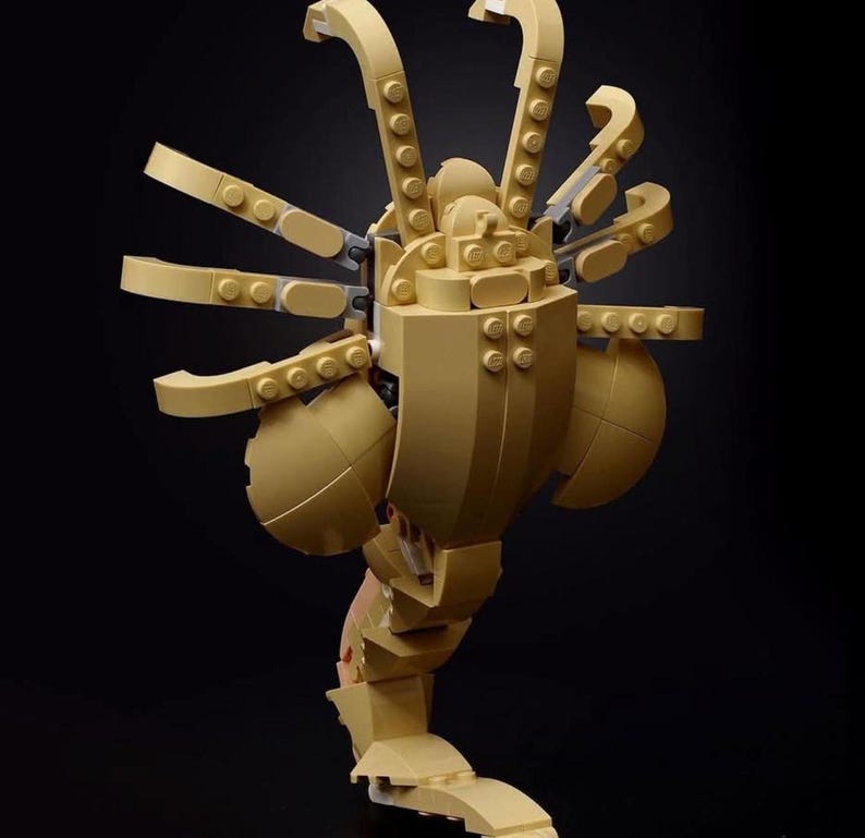 Pode incluir: Um modelo Lego bege de uma criatura alien&iacute;gena com m&uacute;ltiplas pernas e bra&ccedil;os. A criatura est&aacute; em posi&ccedil;&atilde;o de p&eacute; com as pernas dobradas e os bra&ccedil;os levantados.