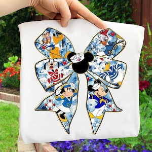 May include: White tote bag featuring a large bow design with Disney characters. The bow has a blue nautical pattern and gold trim. Mickey Mouse, Minnie Mouse, Donald Duck, and Pluto are among the characters featured.