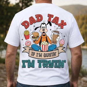 May include: White t-shirt with a cartoon character design holding food and a drink. The shirt displays the text "DAD TAX" and "IF I'M BUYIN' I'M TRYIN'". The design includes a donut, fries, popcorn, and ice cream.