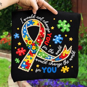 May include: Black fabric with a colorful ribbon design, puzzle pieces, and stars. The ribbon is made of puzzle pieces and flowers. Text reads "I would not change YOU for the world, I would change the world for YOU."