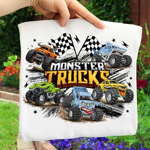 May include: White tote bag with a vibrant graphic of monster trucks. The design showcases monster trucks in orange, blue, green, and yellow, with the text "MONSTER TRUCKS". Checkered flags are also included in the design.