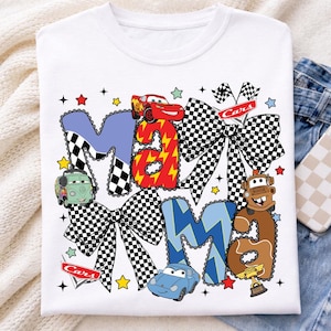 May include: White t-shirt featuring the word "Mama" in a playful design with Cars movie characters. The letters are in blue, red, and brown, with checkered bows and star accents. A fun, colorful graphic tee.