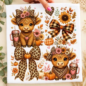 May include: A white fabric print featuring two fluffy highland calves with leopard print bows and bandanas, sunflowers, orange pumpkins, and plaid bows. The design includes leopard print tumblers with heart accents and scattered autumn leaves.