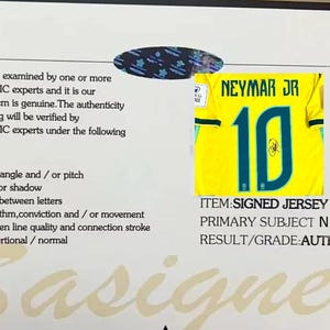 May include: A certificate of authenticity from STARSAUTHENTIC featuring a small image of a yellow Neymar Jr number 10 jersey with a signature. The document lists six verification criteria and states the item is authentic with a large watermark.