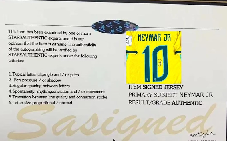 May include: A certificate of authenticity from STARSAUTHENTIC featuring a small image of a yellow Neymar Jr number 10 jersey with a signature. The document lists six verification criteria and states the item is authentic with a large watermark.