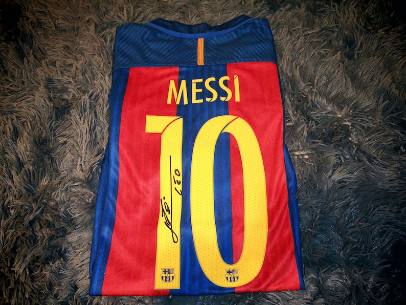 May include: A blue, red, and yellow soccer jersey with the number "10" and the name "MESSI" on the back. The jersey has the FC Barcelona logo on the front and back.
