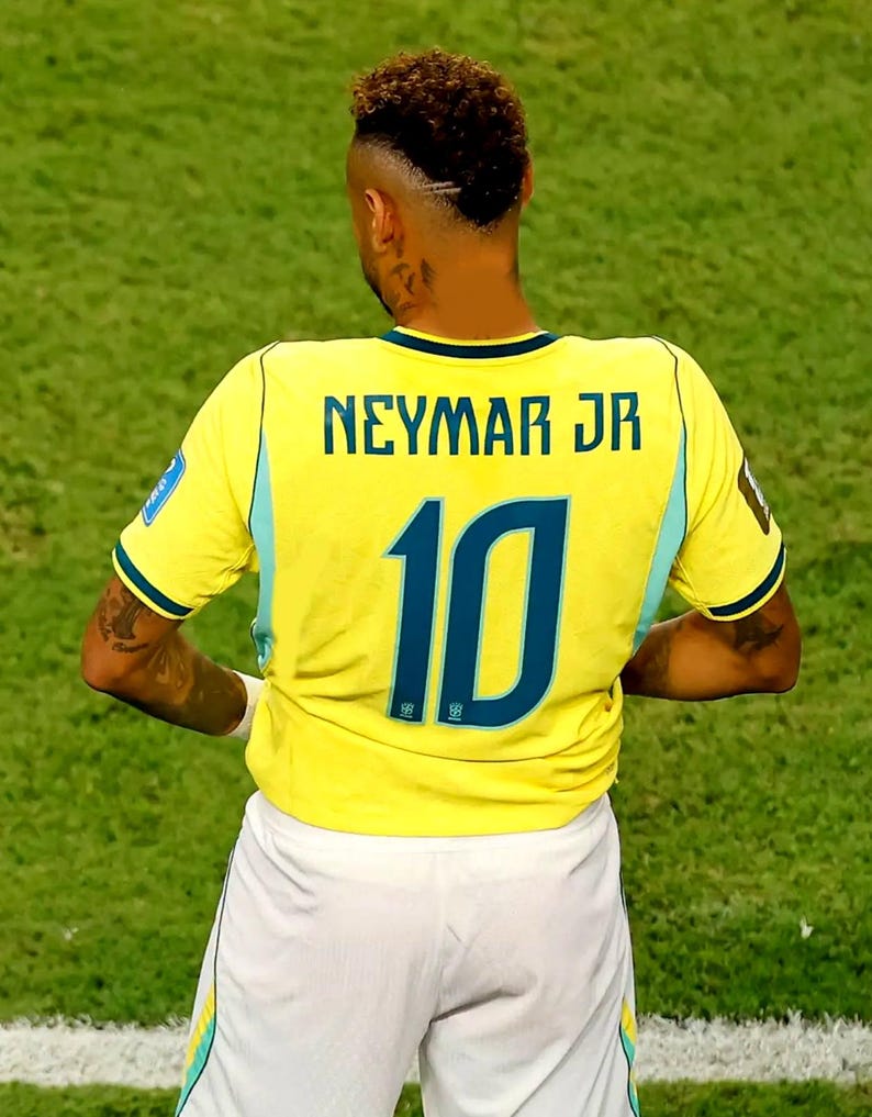 May include: A yellow soccer jersey with the name NEYMAR JR and the number 10 printed in dark blue on the back. The jersey features light blue side panels and is paired with white shorts. The athlete has a short, textured haircut with a shaved line.