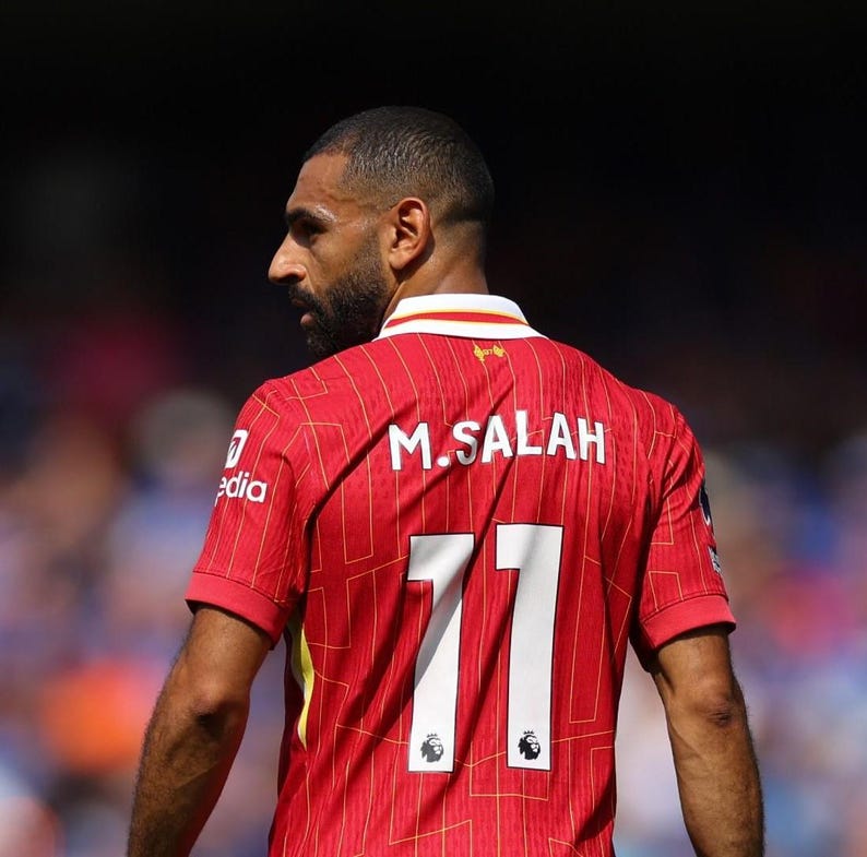 May include: A red soccer jersey with white accents and the name "M. SALAH" and the number "11" on the back.