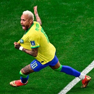 May include: A soccer player wearing a yellow jersey with the name Neymar and the number 10 on the back, paired with blue shorts, green socks, and gold cleats, celebrating on a green field with a white boundary line visible on the grass.