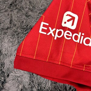 May include: Red and yellow striped soccer jersey with a white Expedia logo on the sleeve.