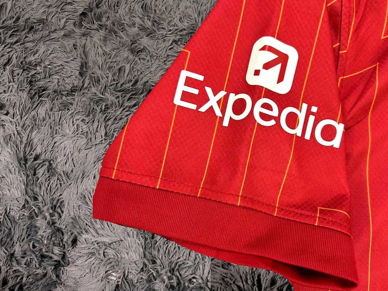 May include: Red and yellow striped soccer jersey with a white Expedia logo on the sleeve.